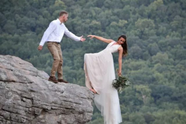 Bride and groom pose for wedding photo shoot hanging off the edge of a cliff (photos)